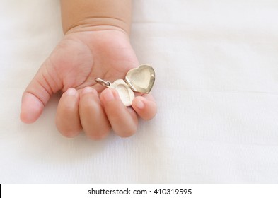 Selective focus of heart locket in baby hand