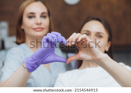 Selective focus of heart shaped hands of dentist and beautiful young woman patient
