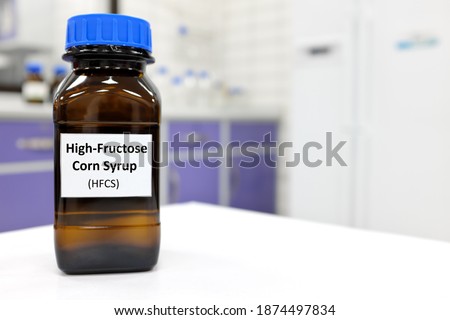 Selective focus of high-fructose corn syrup or hfcs food and beverage sweetener in dark brown glass bottle inside a laboratory.