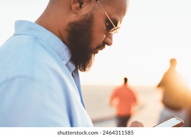 Selective focus, hipster guy checking mail on smartphone sending message via good internet connection on street, young handsome man chatting in social networks using application on telephone outdoors
