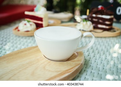 Selective Focus Hot Milk Cup On Background Blurred Strawberry And Chocolate Cake