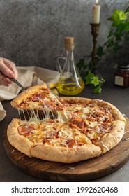 Selective Focus. Hot Pizza With Cheese And Pepperoni. The Girl Pulls A Slice Of Pizza With Melted Cheese Stretching. Vertical Position, Dark Mood