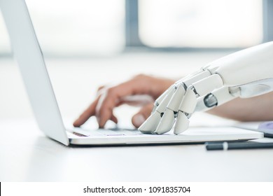 Selective Focus Of Human And Robot Hands Typing On Laptop At Workplace