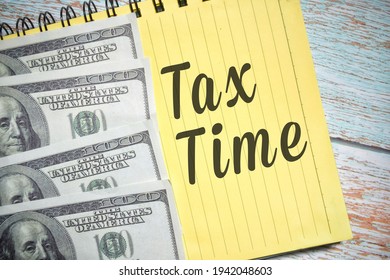 Selective focus image of bank note and Tax Time wording with vintage style over a wooden background. Business and economic concept.