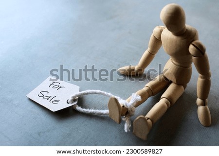 Selective focus image of doll with tag FOR SALE. Human trafficking concept