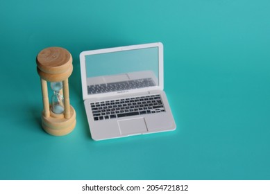 Selective Focus Image Of Hourglass And Laptop On Green Background. Screen Time Limits Concept. 