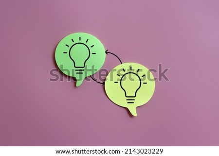 Selective focus image of lightbulb icon on speech bubble and exchange arrow on pink background. Exchange ideas, brainstorming