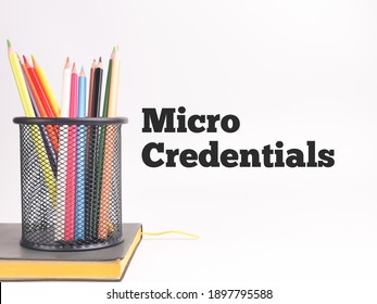 Selective Focus Image With Noise Effect Phrase MICRO CREDENTIALS On White Background With Colorful Pencil And A Book.Education Concept.