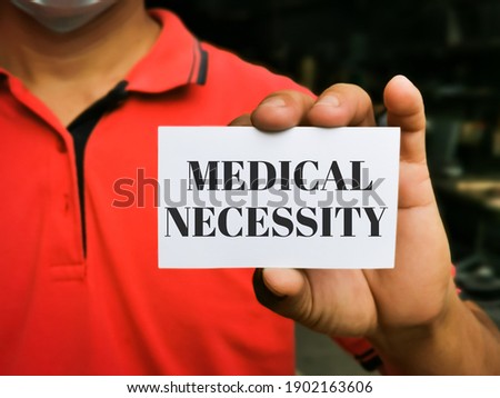 Selective focus image with noise effect hand holding white card with text MEDICAL NECESSITY.Medical concept.