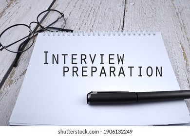 Selective focus image of pen and spectacles with Interview Preparation wording on a wooden background