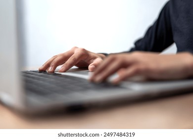 Selective focus image of a person's hands typing on a laptop keyboard.