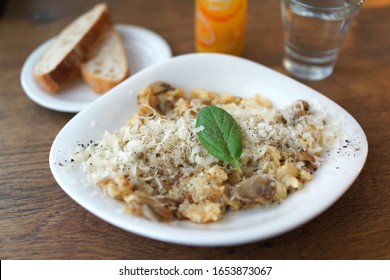 Selective focus image of risotto with mushrooms, fresh herbs and parmesan cheese. Traditional Italian food.
