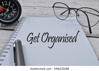 Selective focus image of spectacles,pen and clock with Get Organised wording on wooden background. Business,economy and life concept