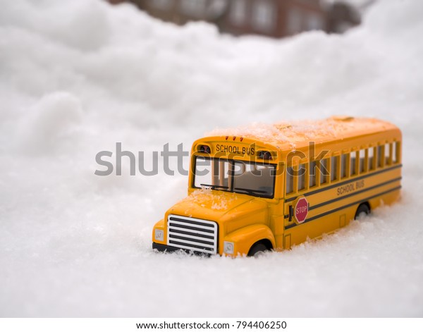 Selective focus Image of yellow school\
bus toy model on the snowing day. / with copy\
space
