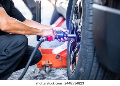 Selective focus to impact air wrench in hand of professional car mechanic working to changing wheel on car. Pneumatic wrench tools. - Powered by Shutterstock