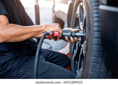 Selective focus to impact air wrench in hand of professional car mechanic working to changing wheel on car. Pneumatic wrench tools. - Powered by Shutterstock