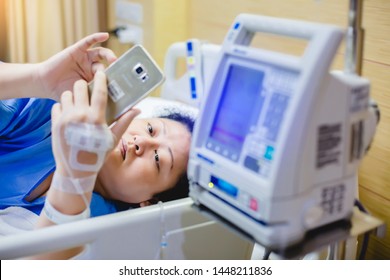 Selective Focus To Infusion Pumps With Blurry Patient Play Smart Phone In Hospital. The Concept Of Working Anytime.