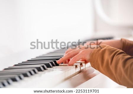 Selective focus to kid fingers and piano key to play the piano. There are musical instrument for concert or learning music. Close up hand of child musician playing the piano on stage.