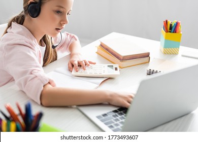 Selective Focus Of Kid In Headset Using Laptop And Calculator During Online Education