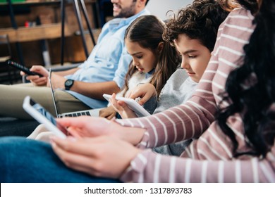 selective focus of kids using gadgets near father and mother at home