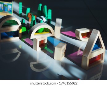 Selective focus of light, shadow and reflection texture learning through various shapes wooden kids toy blocks with colorful transparent glass inside