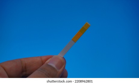 Selective Focus Of Litmus Paper On Hand Isolated On Blue Background. Universal Indicator Paper With Acidic Testing