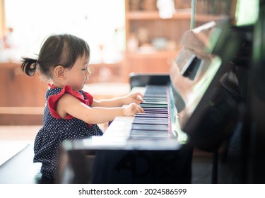 (Selektiver Fokus) Kleines süßes asiatisches Mädchen, das Klavier spielt