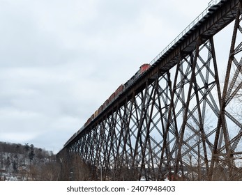 Selective focus low angle view of freight train on 1908 railway trestle bridge seen during a cloudy winter morning, Cap-Rouge area, Quebec City, Quebec, Canada
