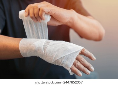 Selective focus of male applying bandage on his hand. People with home safety concept. Close-up.