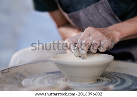 Similar – Young female sitting by table and making clay or ceramic mug