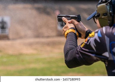 selective focus of man holding and fire handgun in gun shooting competition