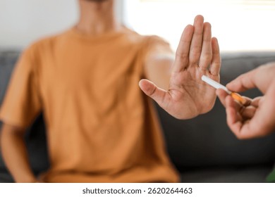 Selective focus of man refusing cigarette indoors. Quitting smoking concept.