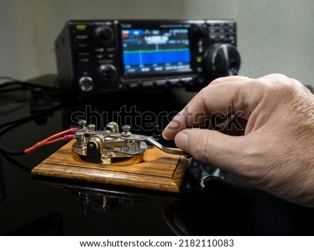 Selective focus of man's hand on a telegraph key with radio defocused in background
