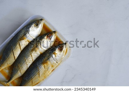 selective focus of marinated fish in a plastic comtainer against white background