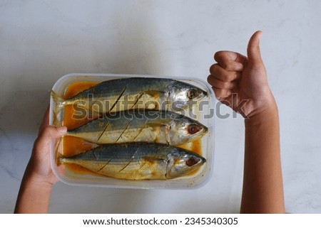 selective focus of marinated fish in a plastic comtainer against white background