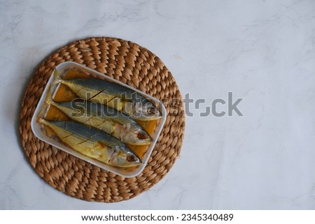 selective focus of marinated fish in a plastic comtainer against white background