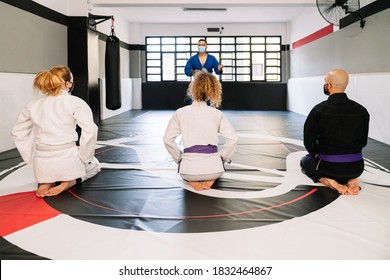 Selective Focus Of Martial Arts Teacher Explaining Best Techniques To Students While Students Are Heard Kneeling On The Mat Wearing Face Masks Due To The Covid19 Coronavirus Pandemic