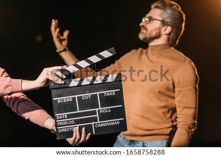 selective focus of mature actor performing role with clapboard in front