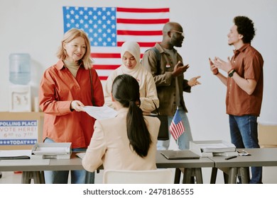 Selective focus medium long shot of ethnically diverse citizens working, voting and chatting at polling place on election day