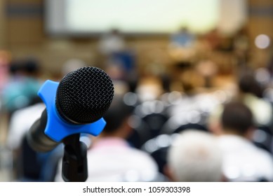 Selective focus microphone in conference hall or meeting room and blurry attendee for seminar business event.