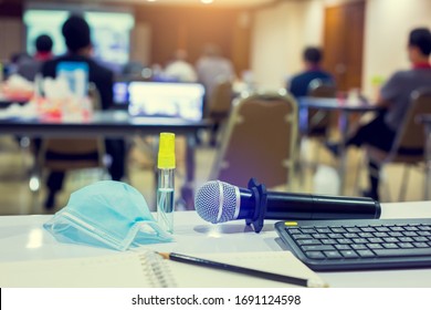 Selective Focus To Microphones , Alcohol Spray And Mask With Blurry Pencil On Notebook In A Meeting Room. Equipment Used In Meetings And Prevent Coronavirus Covid-19 In Business Conference Room.