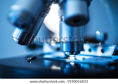 Selective focus of microscope lens on slide against colored background