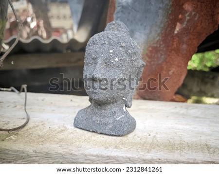 Selective focus of miniature buddha statue head made of clay lying on wooden plank