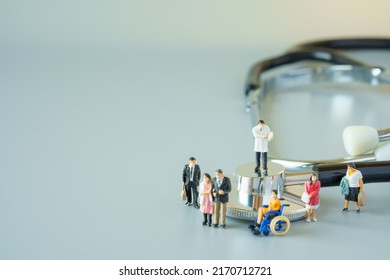 Selective Focus Of Miniature Doctor On Black Stethoscope And Miniature People With Mask On White Ground To Solution For Annual Health Check Up.