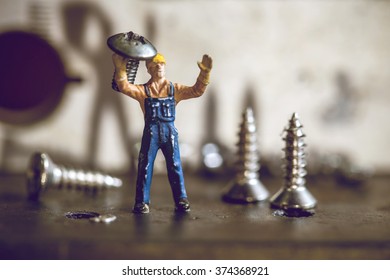 selective focus of miniature worker working with nut and screw,macro photography. vintage color tone.