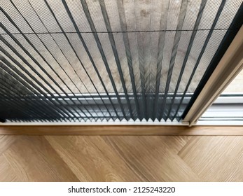 Selective focus mosquito net wire screen on door near wooden floor.