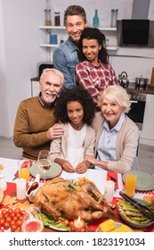 Selective Focus Of Multicultural Family Hugging Near Turkey On Table During Thanksgiving