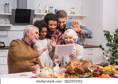 Selective focus of multicultural family waving at digital tablet during video call and thanksgiving celebration - Powered by Shutterstock