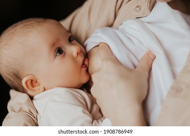 Selective Focus, Noise Effect: Сute Portrait Of A Beautiful Baby Sucking Mom's Breast Touching Lips To The Nipple. Candid Photo At Home 