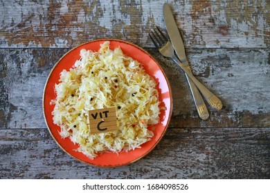  Selektiver Fokus. Beachte die Inschrift Vit C in einem Teller mit Sauerkraut.Konzept für gesunde Lebensmittel. Vitamin-C-haltige Erzeugnisse